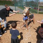 Children playing horseshoes game with hula hoops over a handmade horse