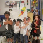 Children dressed as pirates with a pirate ship they built from a table